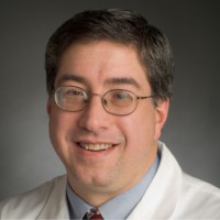 Portrait of a researcher in a lab coat smiling for the camera.