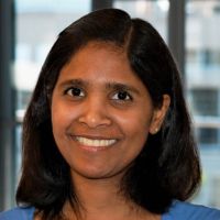 Portrait of a smiling researcher with black hair and a blue shirt.