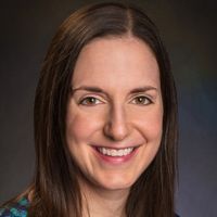Portrait of a smiling woman with long hair, likely a researcher or medical professional.
