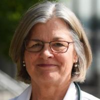 Portrait of a researcher with glasses and short gray hair, smiling outdoors.