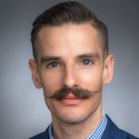 Portrait of a man with a mustache and a professional appearance.