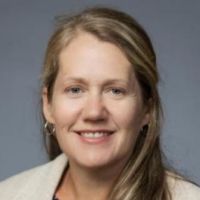 Portrait of a woman smiling, wearing a cream-colored jacket, likely a researcher or healthcare professional.