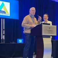 A man and woman speaking at a podium during a cancer research conference.