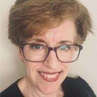 Portrait of a smiling woman with short hair and glasses.