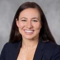 Portrait of a researcher in a professional blazer smiling at the camera.